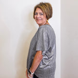 Woman wearing a gray t-shirt standing against a white wall