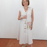 Woman in a white dress standing against a plain background