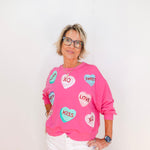 Person wearing a pink sweatshirt with heart-shaped designs on a white background