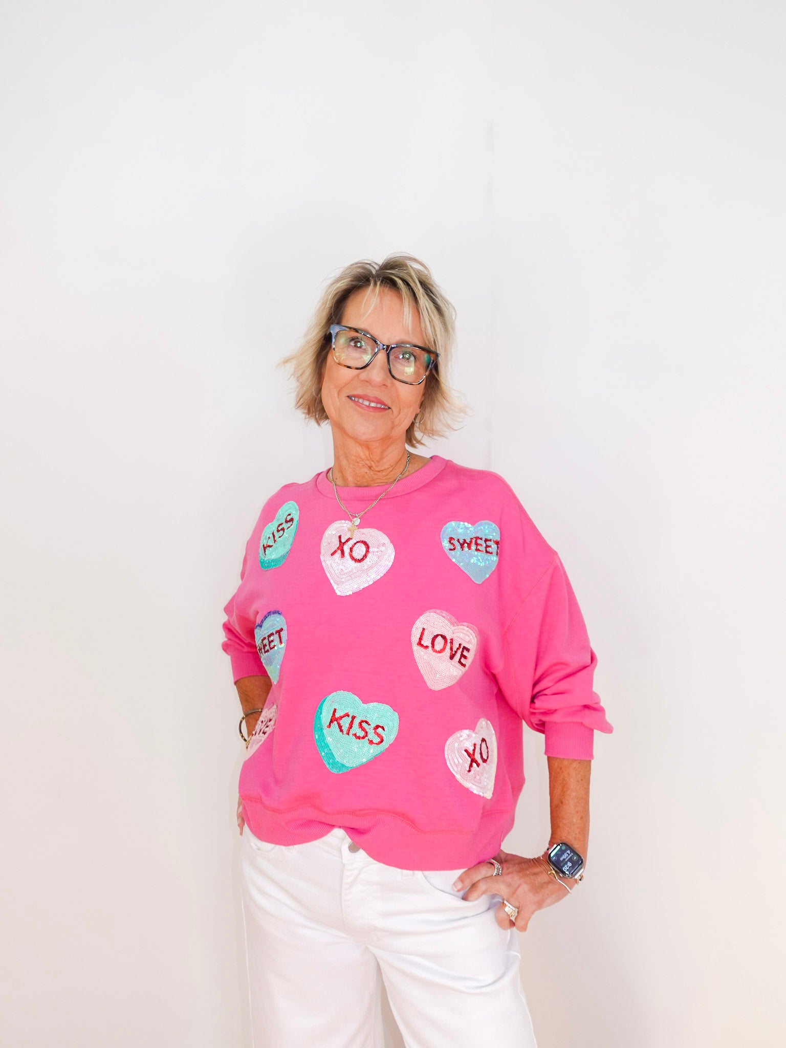 Person wearing a pink sweatshirt with heart-shaped designs on a white background