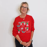 Person wearing a red sweater with 'JOYFUL' text against a white background