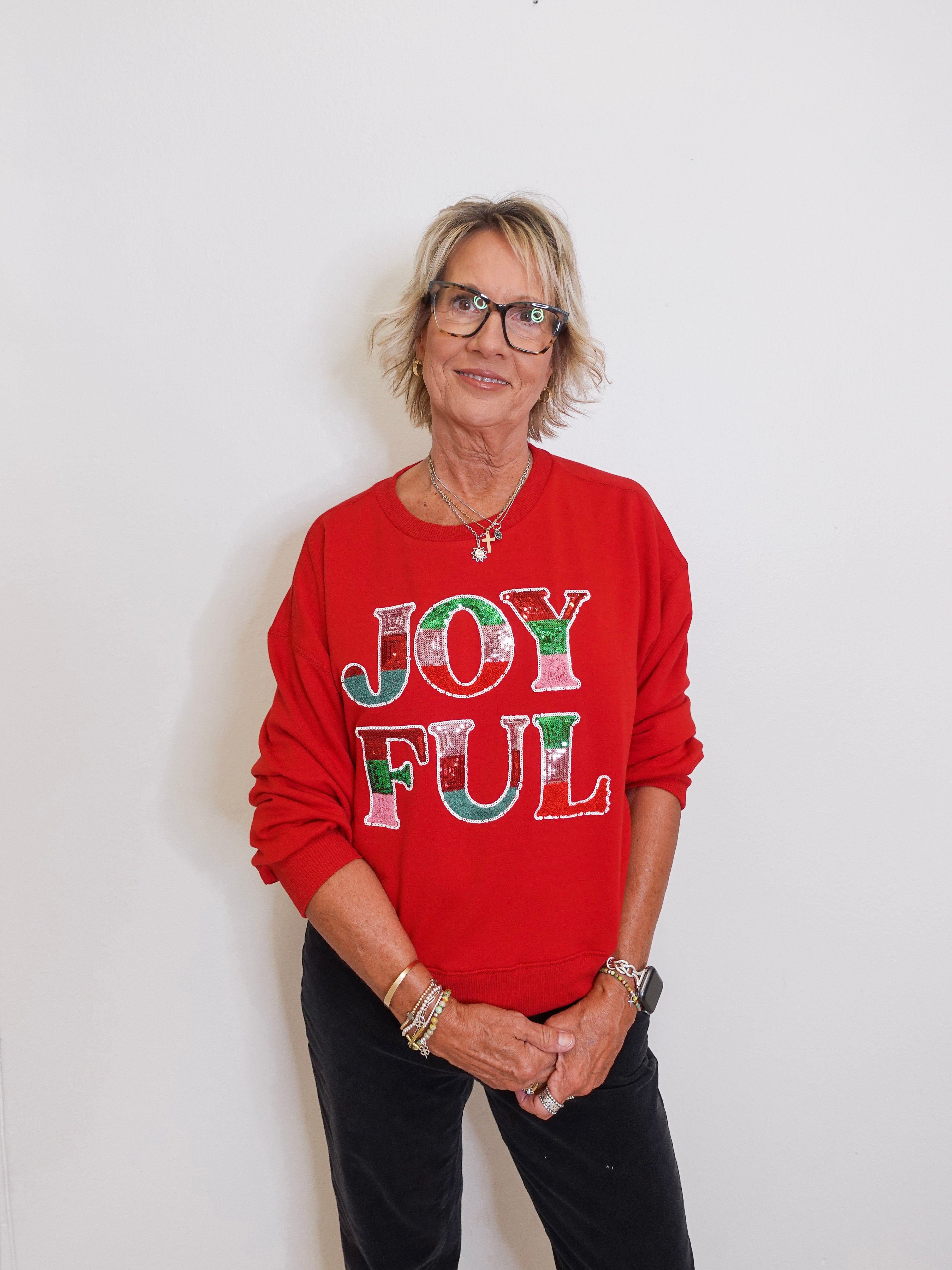 Person wearing a red sweater with 'JOYFUL' text against a white background