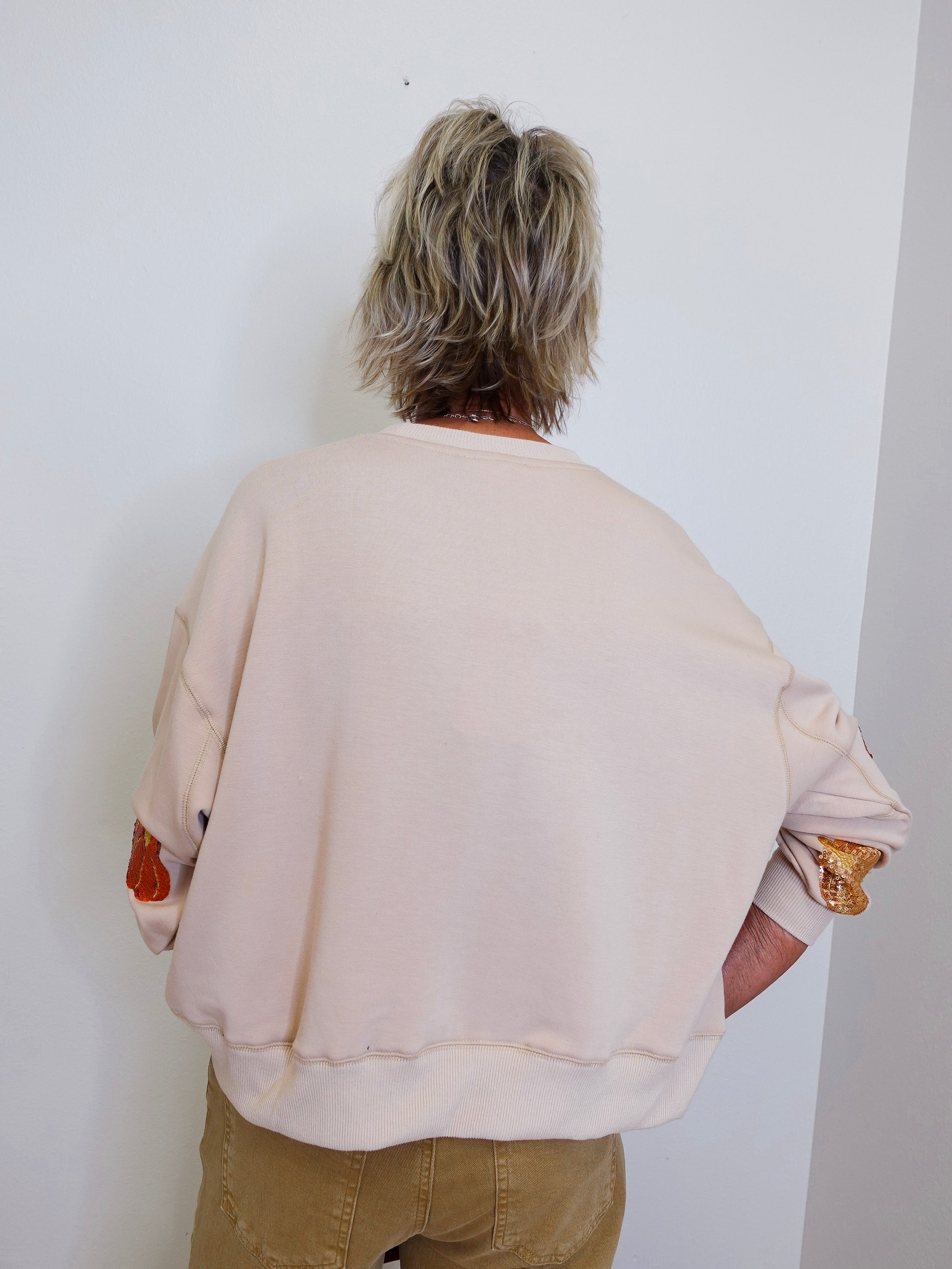 woman wearing a pumpkin sequin sweatshirt