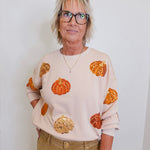 woman wearing a pumpkin sequins sweatshirt against a white background 