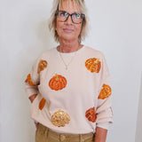 woman wearing a pumpkin sequins sweatshirt against a white background 