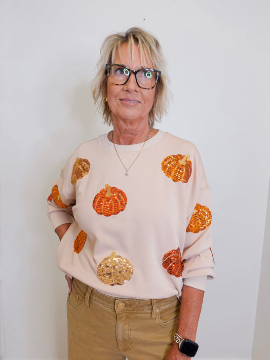 woman wearing a pumpkin sequins sweatshirt against a white background 