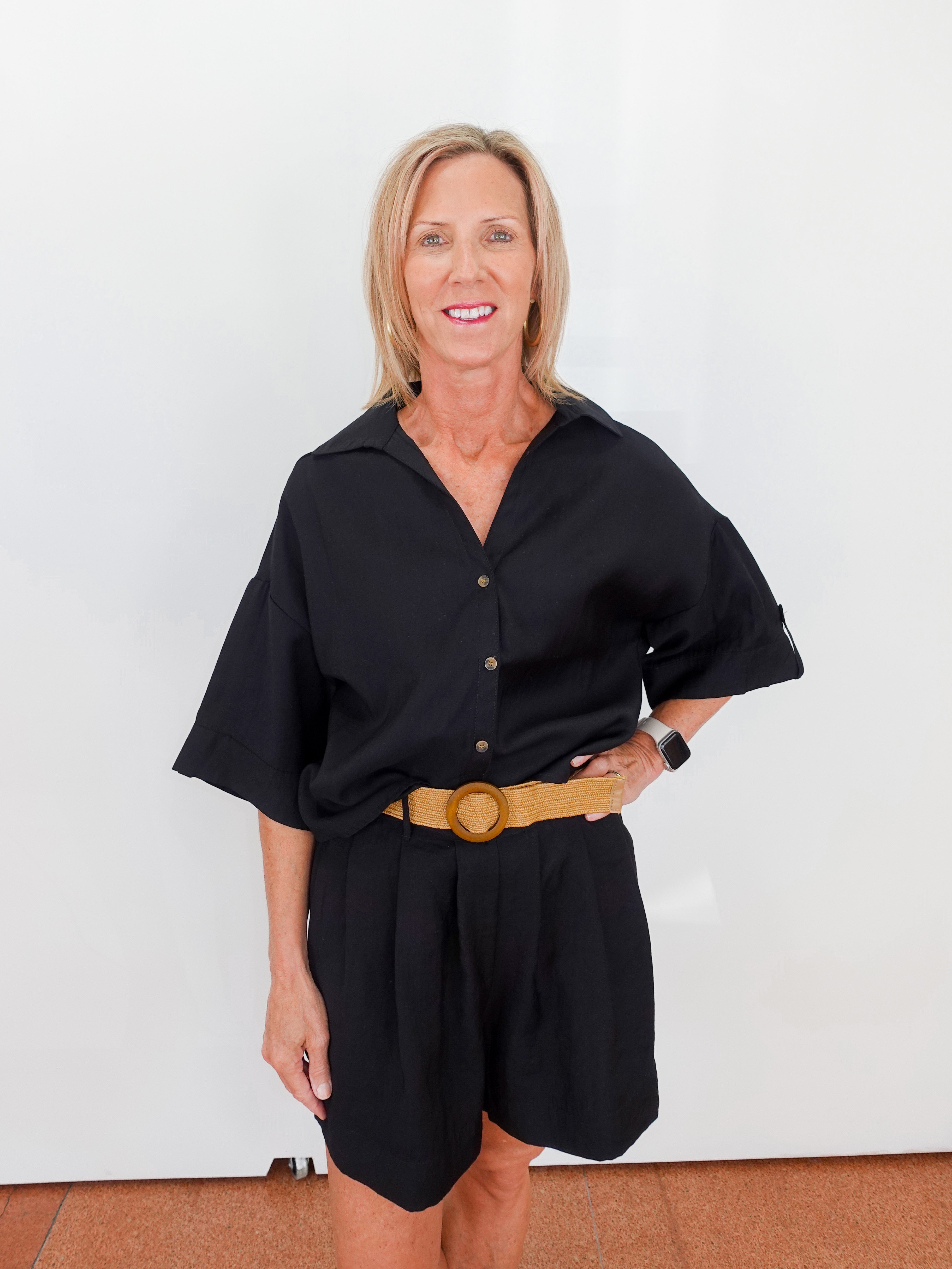 Woman wearing a black outfit with a yellow belt against a white background