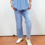 Person wearing a blue top and light blue jeans with white sneakers on a plain background