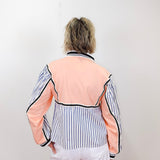 Person wearing a peach and black striped top with white pants against a plain background