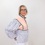 Person wearing a striped shirt with a sheer overlay against a white background