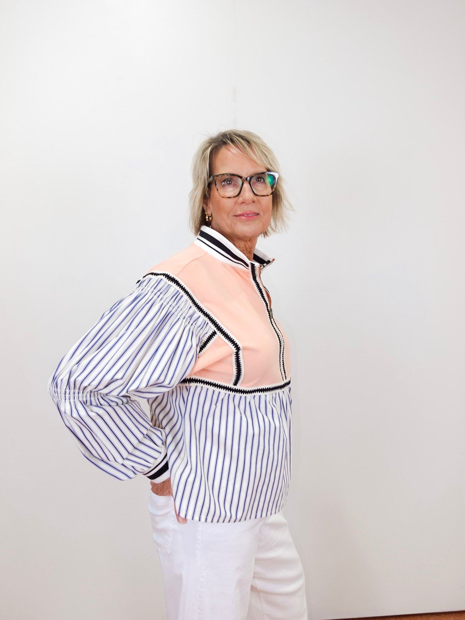 Person wearing a striped shirt with a sheer overlay against a white background