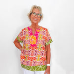 Woman wearing a colorful patterned top against a white background