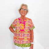 Woman wearing a colorful patterned top against a white background