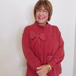 Woman wearing a red sweater with a bow design against a white background