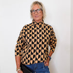 A woman modeling a mock neck heart pattern sweater in front of a white wall. 