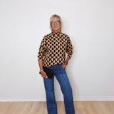 A woman modeling a mock neck heart pattern sweater in front of a white wall. 