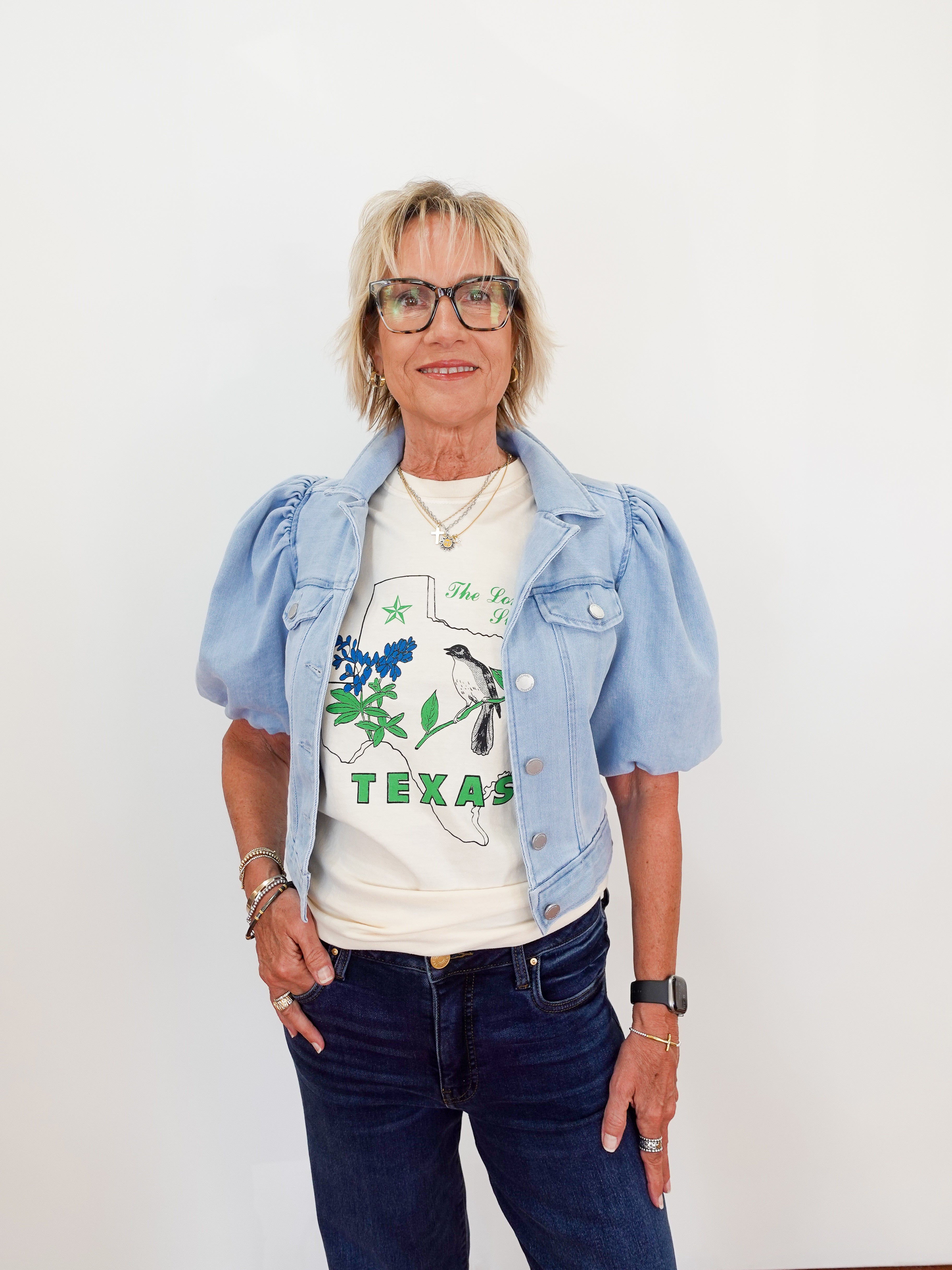 Woman wearing a denim jacket over a graphic t-shirt with 'Texas' text on a white background