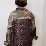Person wearing a camouflage and leopard print shirt against a white wall