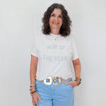 Woman wearing a white t-shirt with text and light blue shorts against a plain background