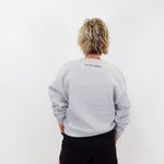 Person wearing a gray sweatshirt with text on the back against a white background