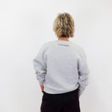 Person wearing a gray sweatshirt with text on the back against a white background