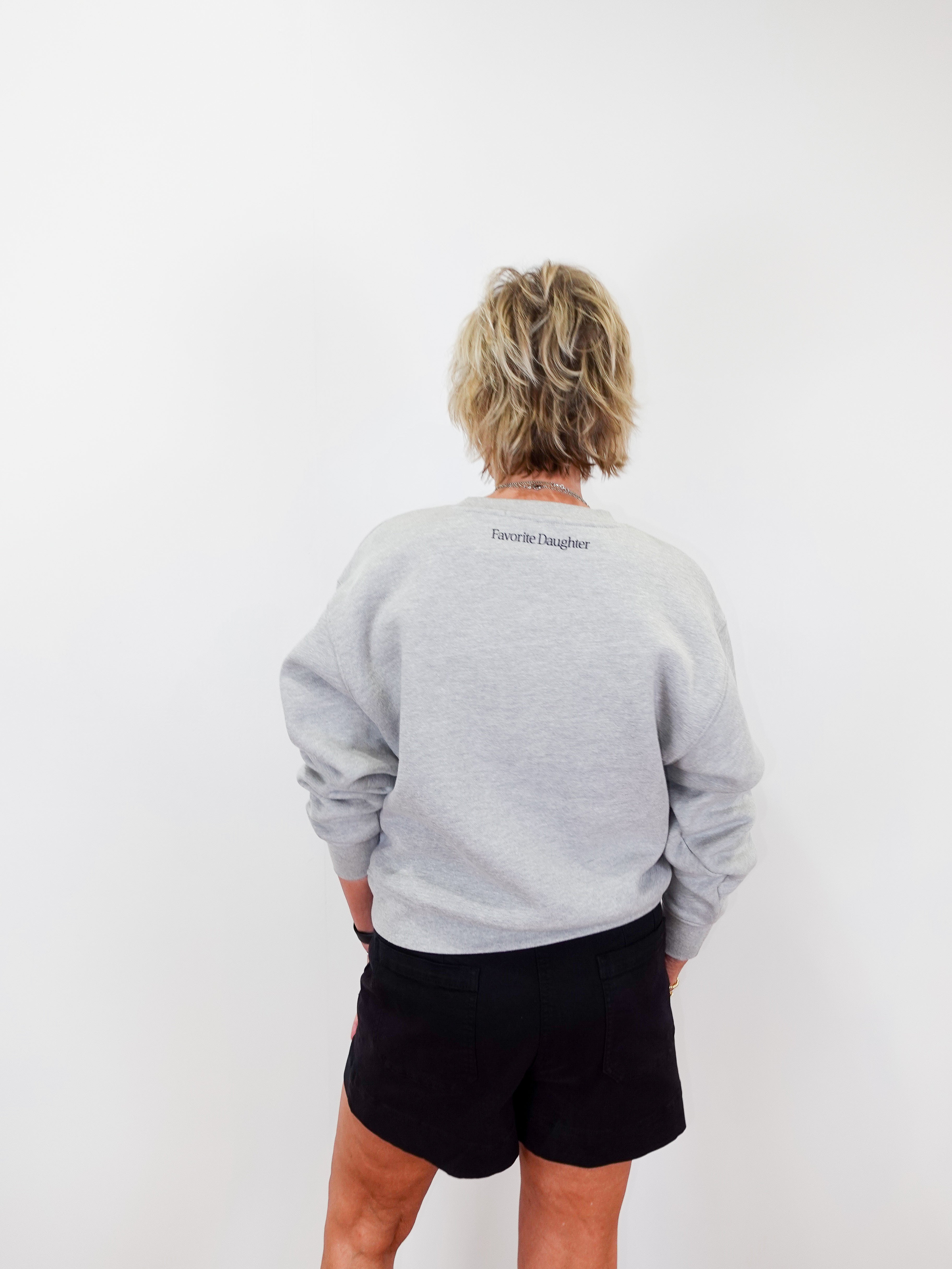 Person wearing a gray sweatshirt with text on the back against a white background