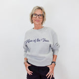 Woman wearing a gray sweatshirt with 'Mom of the Year' text on a white background