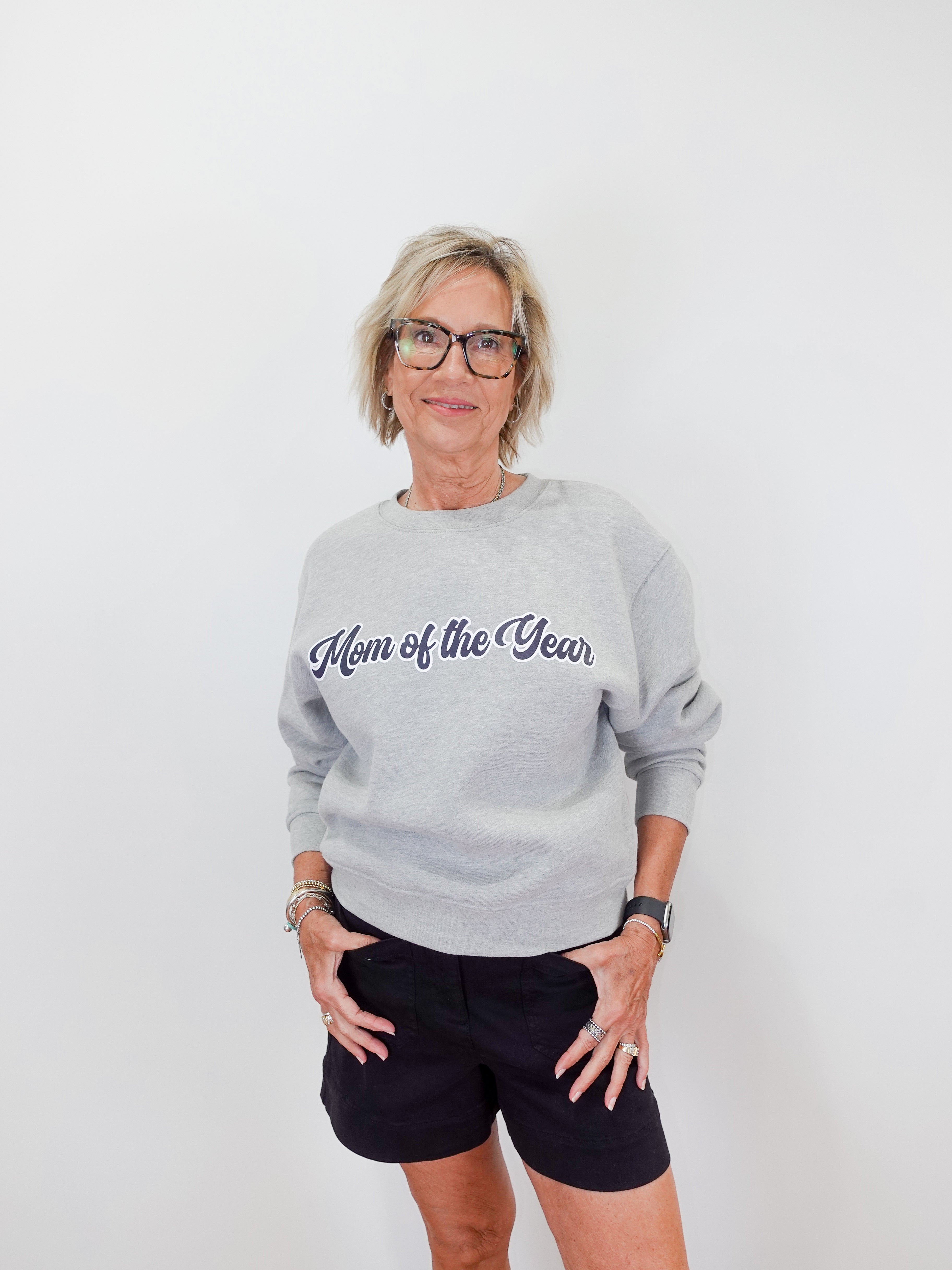 Woman wearing a gray sweatshirt with 'Mom of the Year' text on a white background