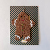 Decorative gingerbread man ornament on a striped card with a plain background