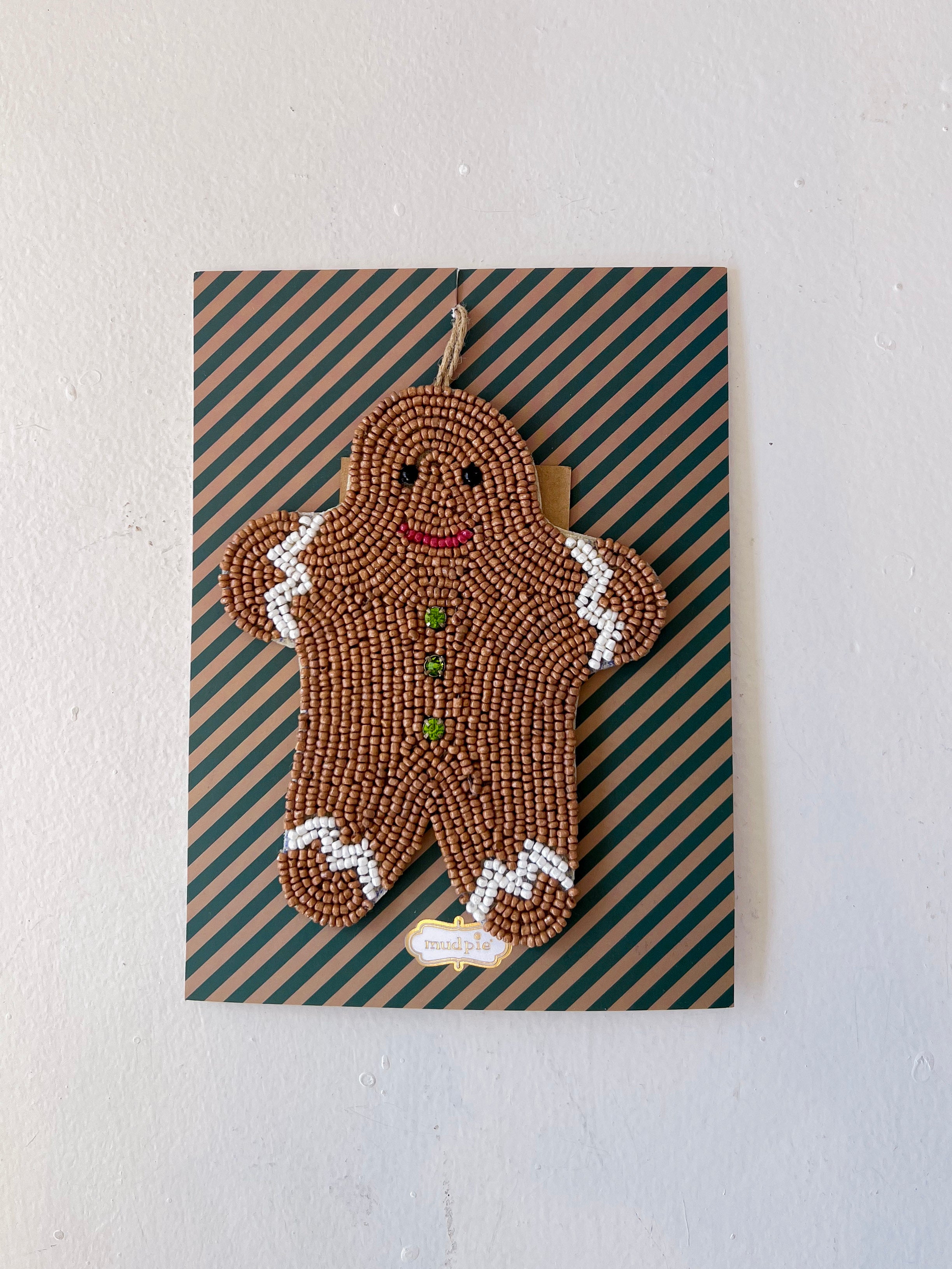 Decorative gingerbread man ornament on a striped card with a plain background
