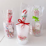 Three clear gift bags with colorful spoons and text on a white surface