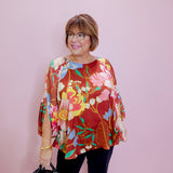 Woman wearing a colorful floral blouse against a plain background