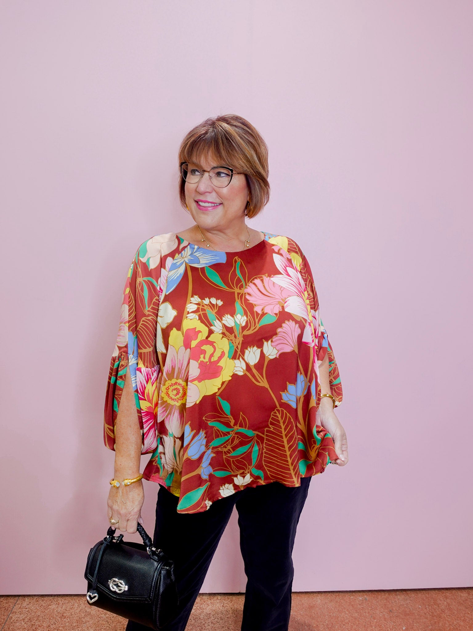 Woman wearing a colorful floral blouse against a plain background