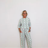 Person wearing a green and white patterned outfit against a white wall.