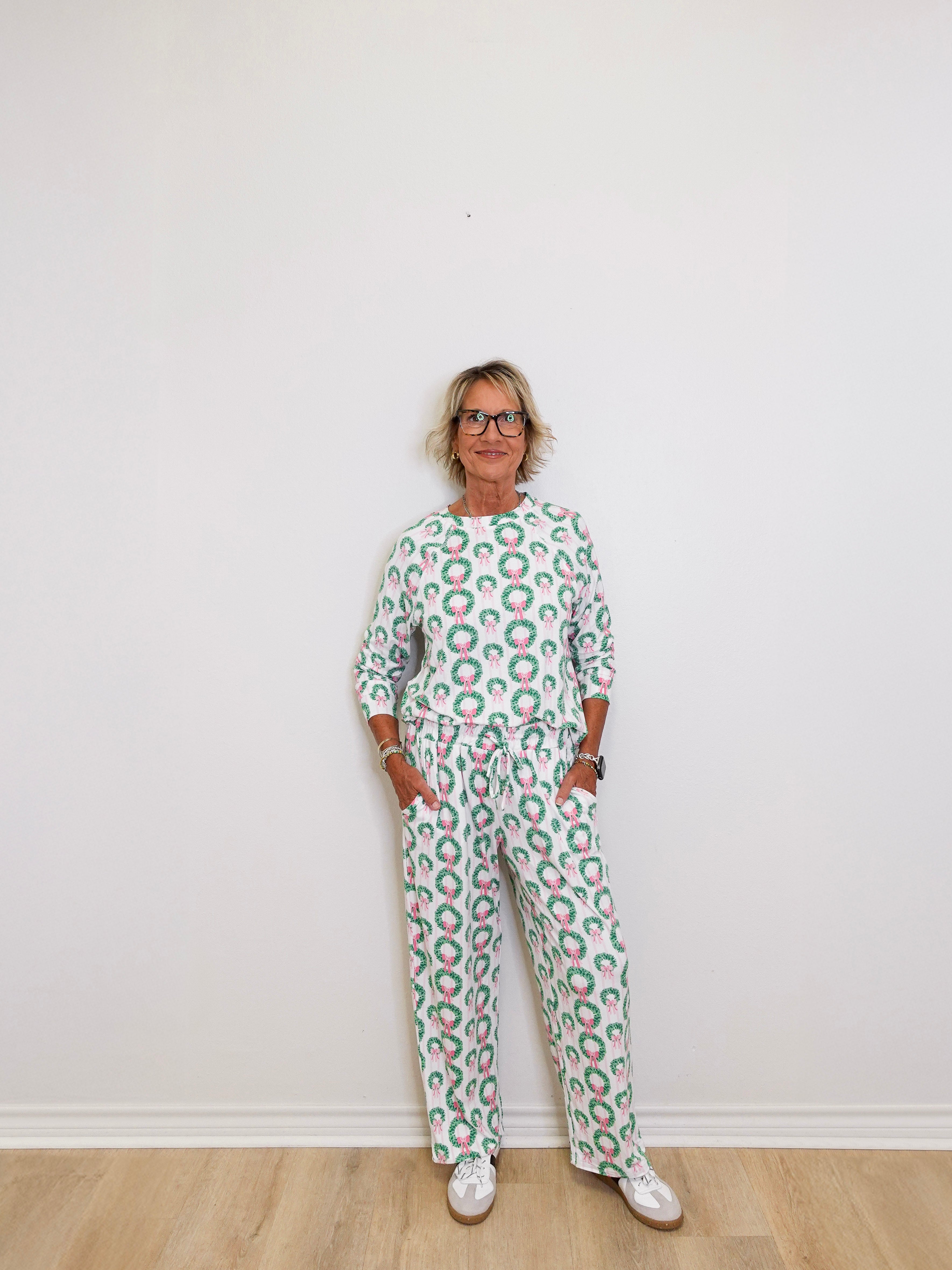 Person wearing a green and white patterned outfit against a white wall.