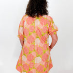Person wearing a floral dress with pink and green flowers on a white background