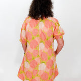 Person wearing a floral dress with pink and green flowers on a white background