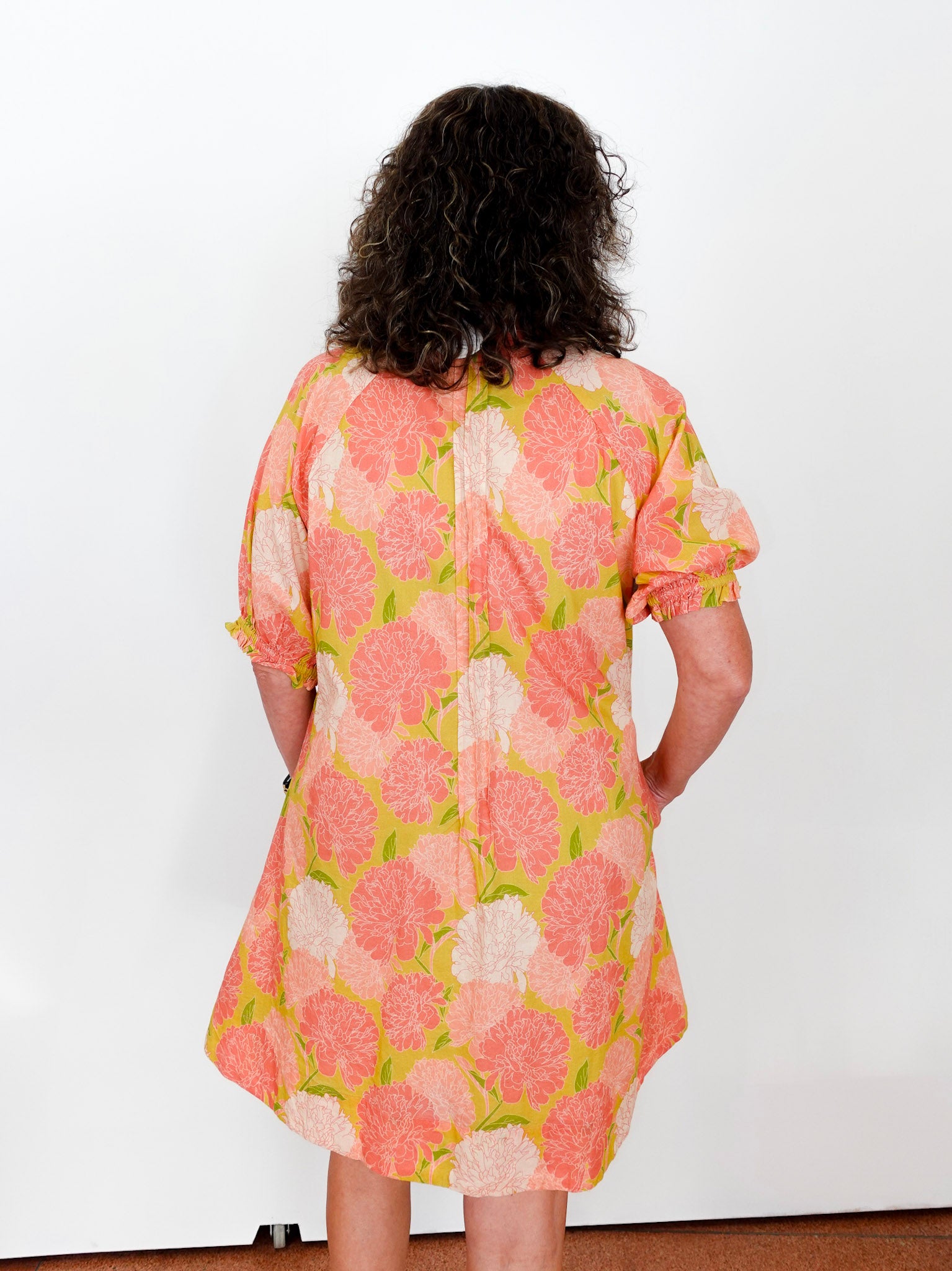 Person wearing a floral dress with pink and green flowers on a white background