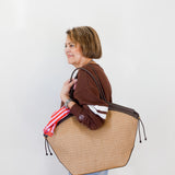 Woman holding a large woven bag against a plain background