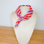Red and white striped scarf on a mannequin head against a plain background