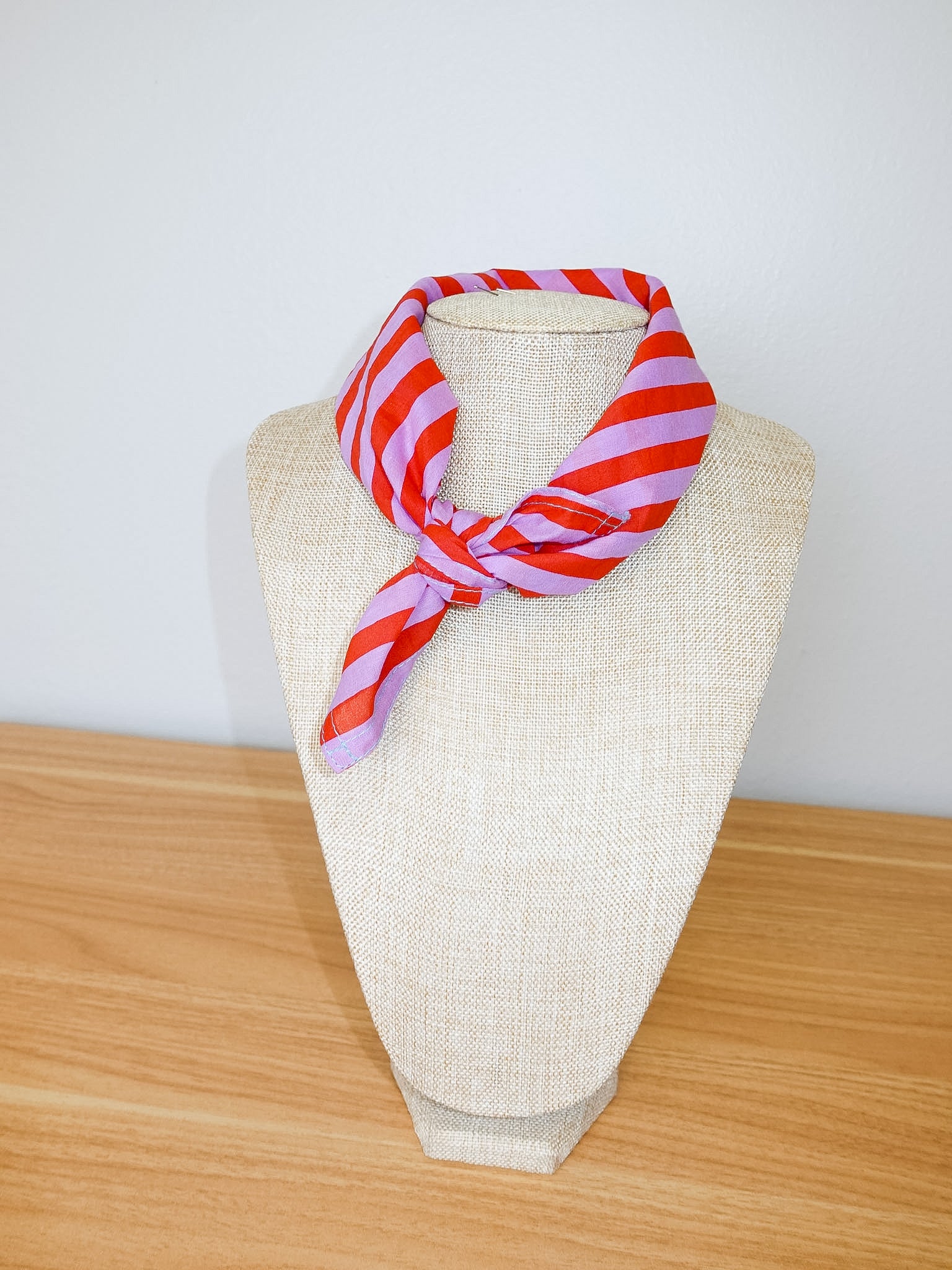 Red and white striped scarf on a mannequin head against a plain background