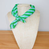 Green and blue striped scarf on a mannequin head against a white background