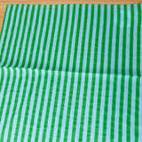 Green and light blue striped fabric on a wooden surface