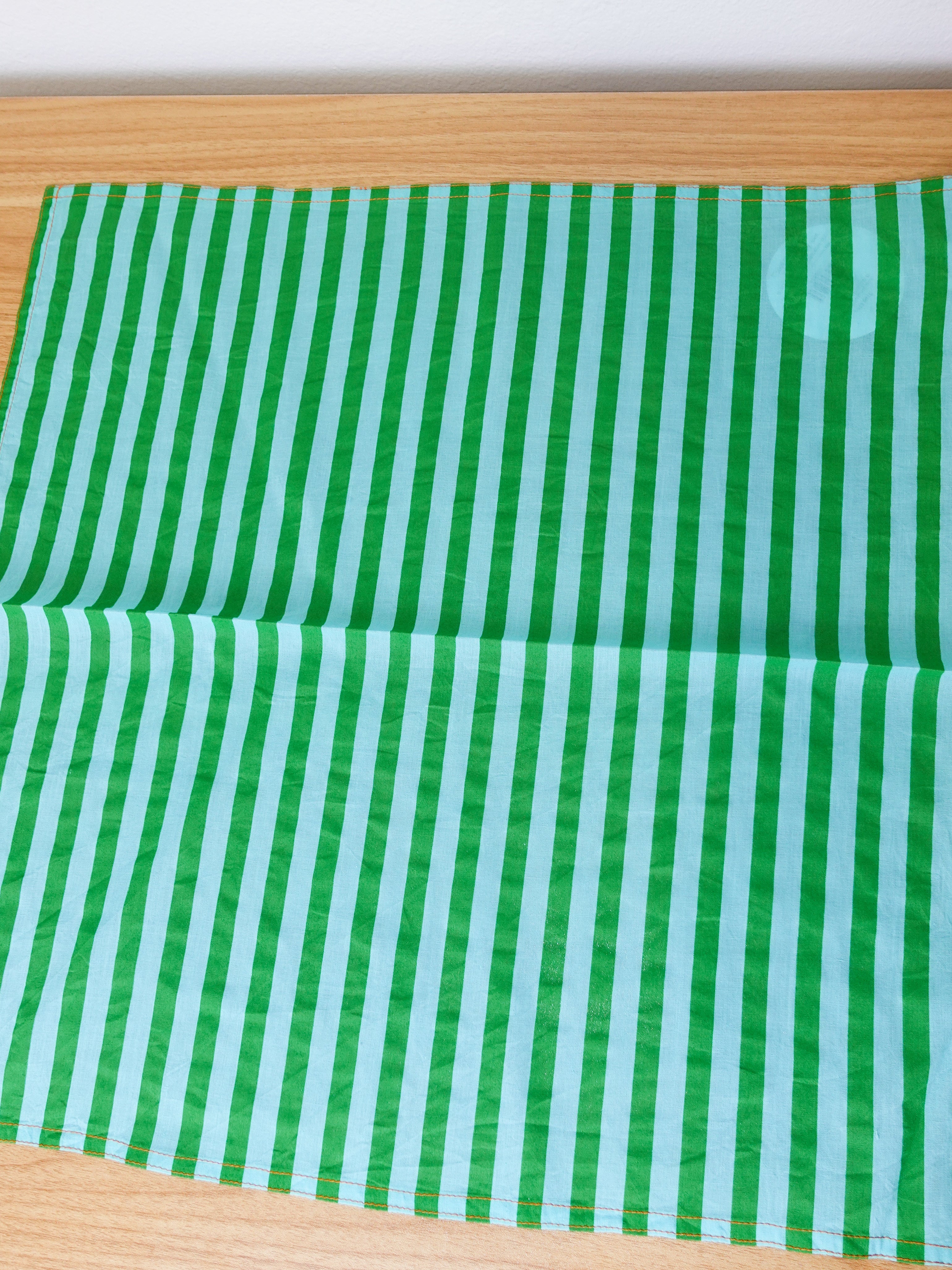 Green and light blue striped fabric on a wooden surface