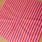 Red and pink striped fabric on a wooden surface