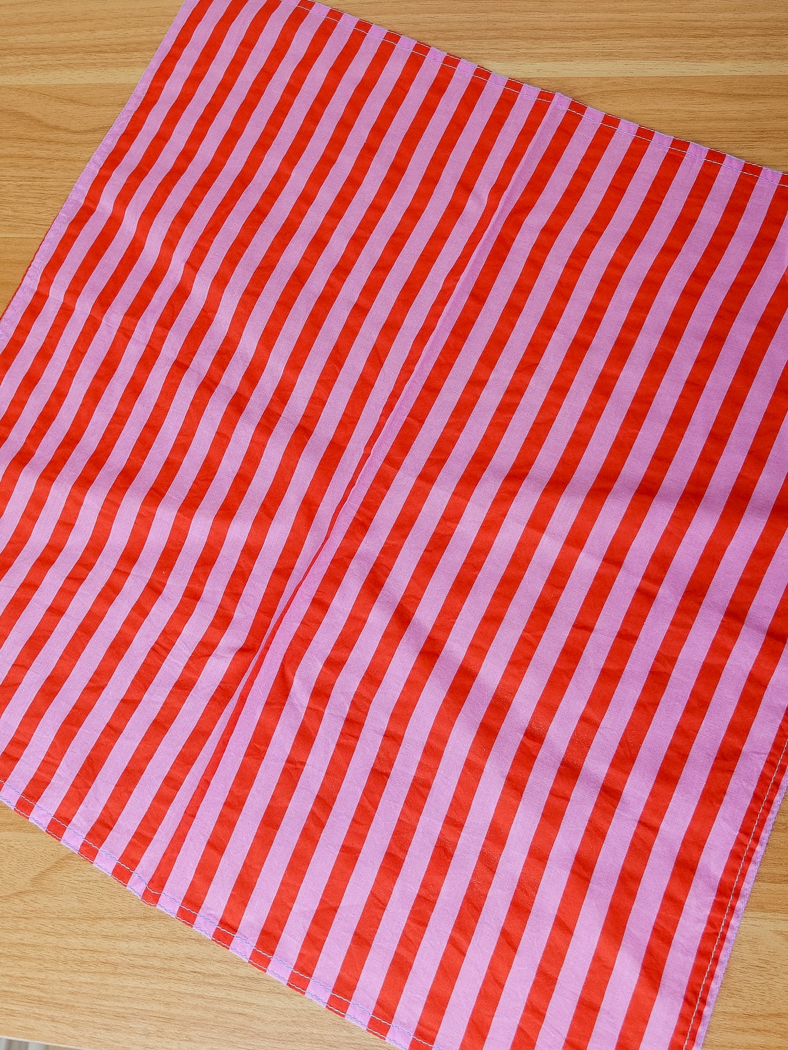 Red and pink striped fabric on a wooden surface