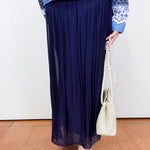 White textured blouse styled with a navy silk foldover waist skirt and blue patterned jacket.