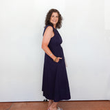 Woman wearing a navy blue dress standing against a white wall.