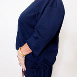 Navy blue ribbed sweater worn by a person on a white background