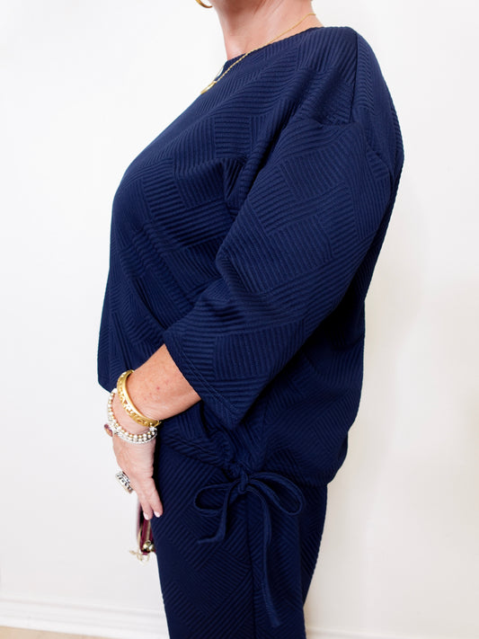 Navy blue ribbed sweater worn by a person on a white background